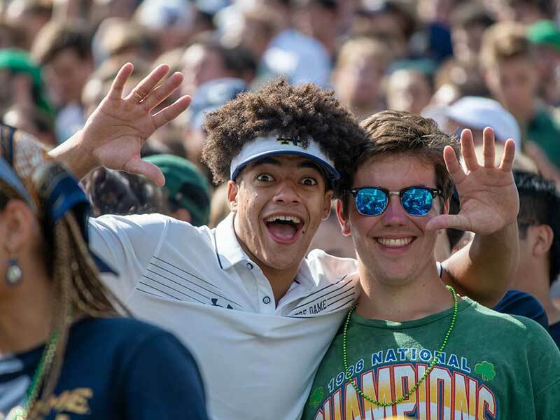 Two smiling young men in focus in a sea of students in a crowd.